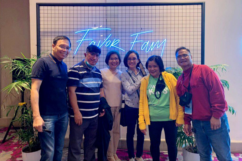 People standing in front of neon 'Favor Fam' sign.